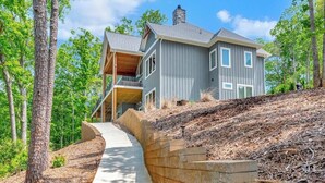 A modern two-story house with a covered porch and a stone retaining wall.