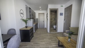 Une chambre d’hôtel moderne dotée d’une kitchenette, d’un coin repas avec une table et des chaises, d’un canapé et d’une table basse en bois.
