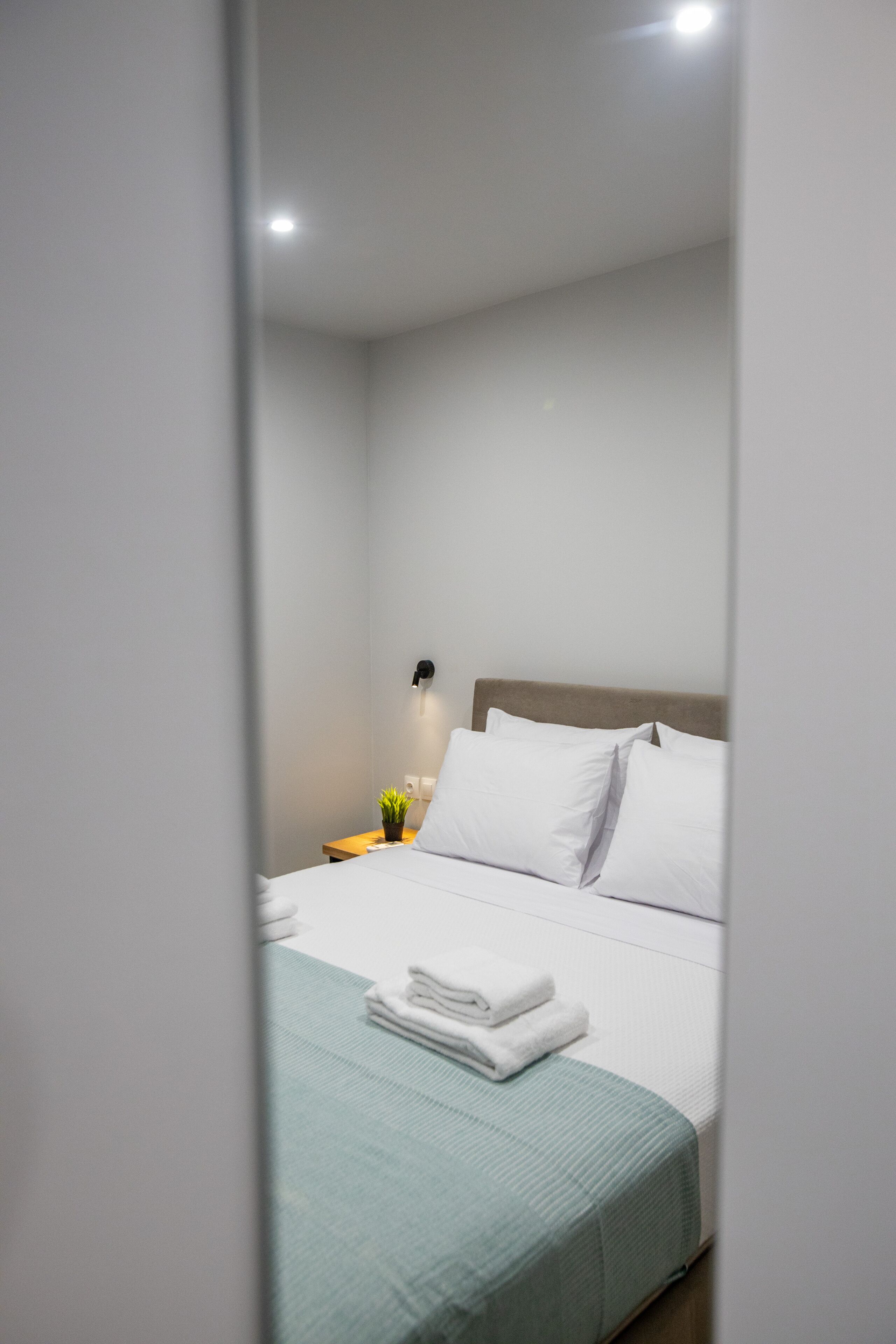 Una habitación de hotel con una cama, una mesita de noche y una lámpara de pared.