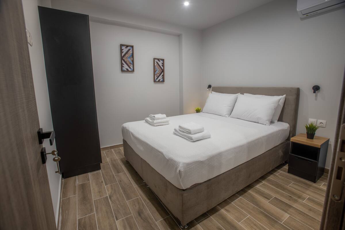 Une chambre d’hôtel moderne avec un grand lit, une table de chevet avec une lampe et une petite plante.