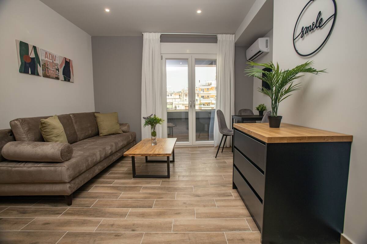 Un salon moderne avec un canapé, une table basse, un petit bureau et une plante en pot.