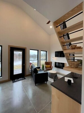 Relax in a spacious living area with a comfortable sofa and armchair, perfect for lounging. Enjoy a flat-screen TV and a casual dining or work space.