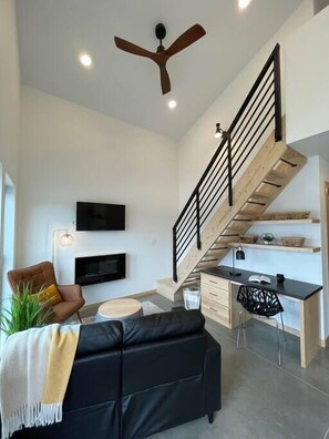 Relax in a stylish living space with a leather sofa, dining table, and staircase.