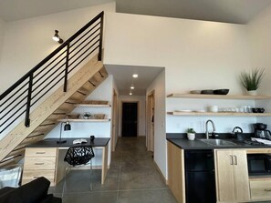 Modern kitchen with dishwasher, sink, and coffee machine, plus a dining area with a small table and chair.