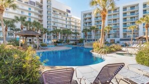 A hotel with multiple floors, a swimming pool, and lounge chairs.