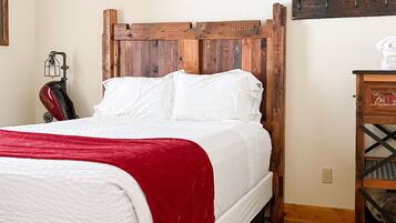 A bed with a wooden headboard, white bedding, and a red throw blanket.