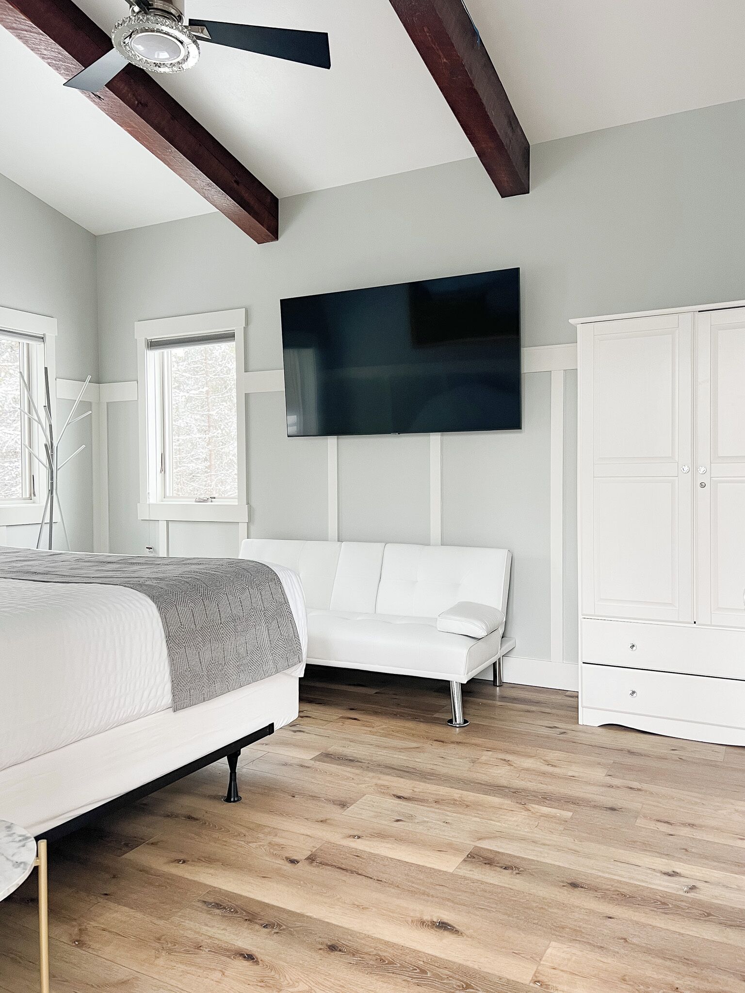 Une chambre à coucher avec un lit, un canapé blanc, une armoire et un ventilateur de plafond.