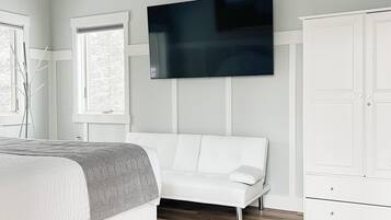 Une chambre à coucher avec un lit, un canapé blanc, une armoire et un ventilateur de plafond.
