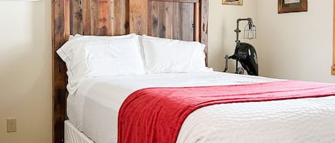 A bed with a wooden headboard, white bedding, and a red throw blanket.