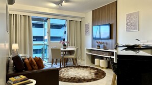 Een moderne hotelkamer met balkon, eethoek, flatscreen-tv en bureau met computer.