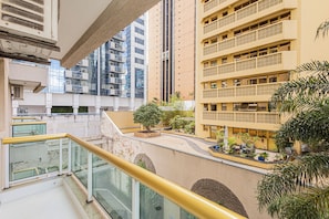Un immeuble résidentiel à plusieurs étages, doté de balcons, d’une cour intérieure agrémentée de plantes et d’une rambarde en verre.
