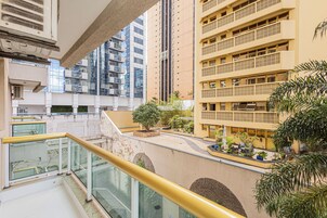 Un edificio residencial de varios pisos con balcones, un patio central con plantas y barandilla de vidrio.