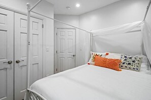 Ein Schlafzimmer mit einem weißen Himmelbett, weißen Wänden und einer weißen Tür.