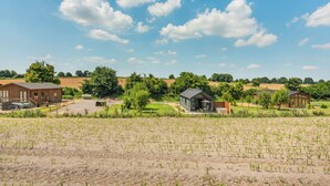 Ländliche Landschaft mit Feldern, einem Bauernhaus und einem kleinen Gebäude.