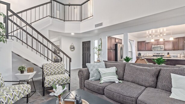 A modern living room with a staircase, a sofa set, a coffee table, and a kitchen area in the background. - Your Home Away! Offering free heated pool ! Close to almost everything! (Chandler)