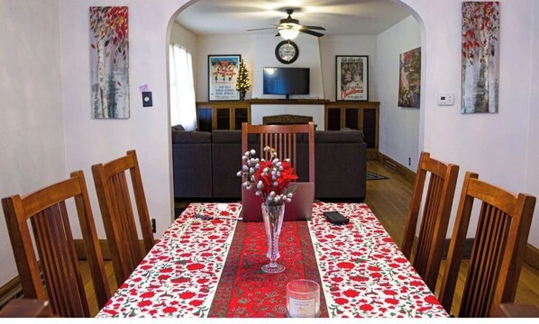 Uma área de refeições com uma mesa posta para quatro pessoas, um vaso com flores e uma vela.