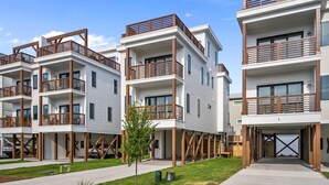 A modern multi-story residential building with balconies, a covered entrance, and a small tree in the front yard. - Modern Single Family Home 5 minute walk to the Beach! Linens Included! (Carolina Beach)