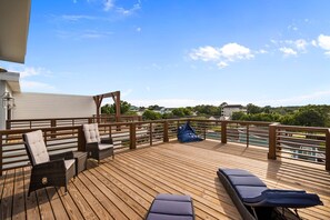 Une terrasse en bois avec des chaises longues et une pergola, donnant sur une piscine et un espace verdoyant.