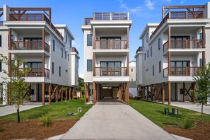 Un immeuble d’appartements moderne doté d’une entrée centrale, de nombreux balcons et d’une pelouse bien entretenue.