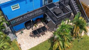 Une maison bleue dotée d’un patio comprenant une table et des chaises, le tout entouré de palmiers.