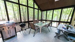 A covered outdoor dining area with a grill, table, and chairs. - GreatRoom, soaring ceilings, window walls,F/Place Just what you are looking for. (Bushkill)