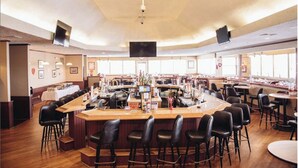 A spacious bar area with multiple seating options, including bar stools and tables, and a central counter with a variety of items displayed. - GreatRoom, soaring ceilings, window walls,F/Place Just what you are looking for. (Bushkill)
