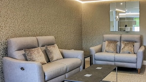 A modern living room with two grey sofas, a coffee table, and a patterned carpet.