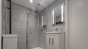 A modern bathroom with a glass-enclosed shower, a white toilet, and a vanity with a mirror.
