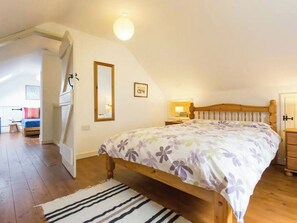 Ein Schlafzimmer mit einem hölzernen Bett, einem Nachttisch, einem Spiegel und einer Tür.