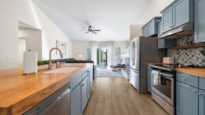 Een moderne keuken met een houten aanrecht, roestvrijstalen apparatuur en blauwe kastjes.
