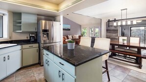 A modern kitchen with a central island, built-in appliances, and a dining area with a bench and table. - Bright Centrally located home in Sedona (Sedona)