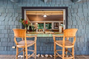 A dining area with two wooden chairs and a table, a ceiling fan, and a view of the interior through a window.