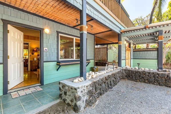 A house with a covered porch, a stone retaining wall, and a door leading to the interior.