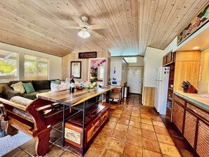 A kitchen with a wooden ceiling, a dining table with chairs, a refrigerator, and a microwave.