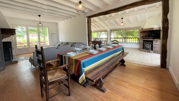 A spacious dining area with a long wooden table set for four, a bench, and a fireplace in the background.