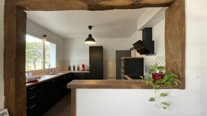 A modern kitchen with a rustic wooden arch, a central island, and a hanging plant.