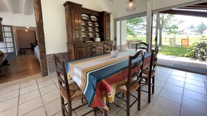 A dining area with a table set for four, wooden chairs, a patterned tablecloth, and a wooden cabinet with dishes.