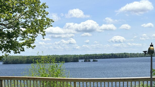 A deck with a fire pit, Adirondack chairs, and a view of a lake. - Waterfront Cottage on the Upper Rideau Lake (Westport)