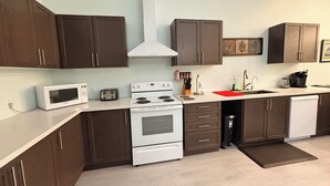 A modern kitchen with dark brown cabinets, a white stove, a microwave, and a dishwasher. - Waterfront Cottage on the Upper Rideau Lake (Westport)