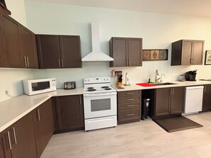 A modern kitchen with dark brown cabinets, a white stove, a microwave, and a dishwasher.