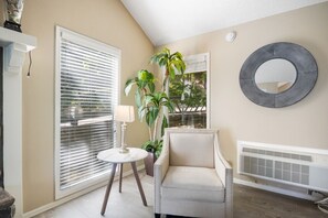Relax in this inviting space with a comfortable armchair, round table, and potted plant.