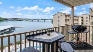 Ein Balkon mit Seeblick, einem Grill und Sitzgelegenheiten im Freien.