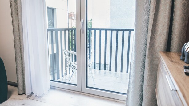 Habitació amb una porta corredissa de vidre que dona a un balcó exterior amb barana metàl·lica.