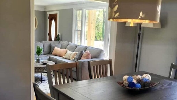 A dining area with a dark wooden table and chairs, a bowl of decorative items, and a hanging lamp. - Lake Front Haven with Dual Living Rooms, Hot Tub (Mt. Juliet)