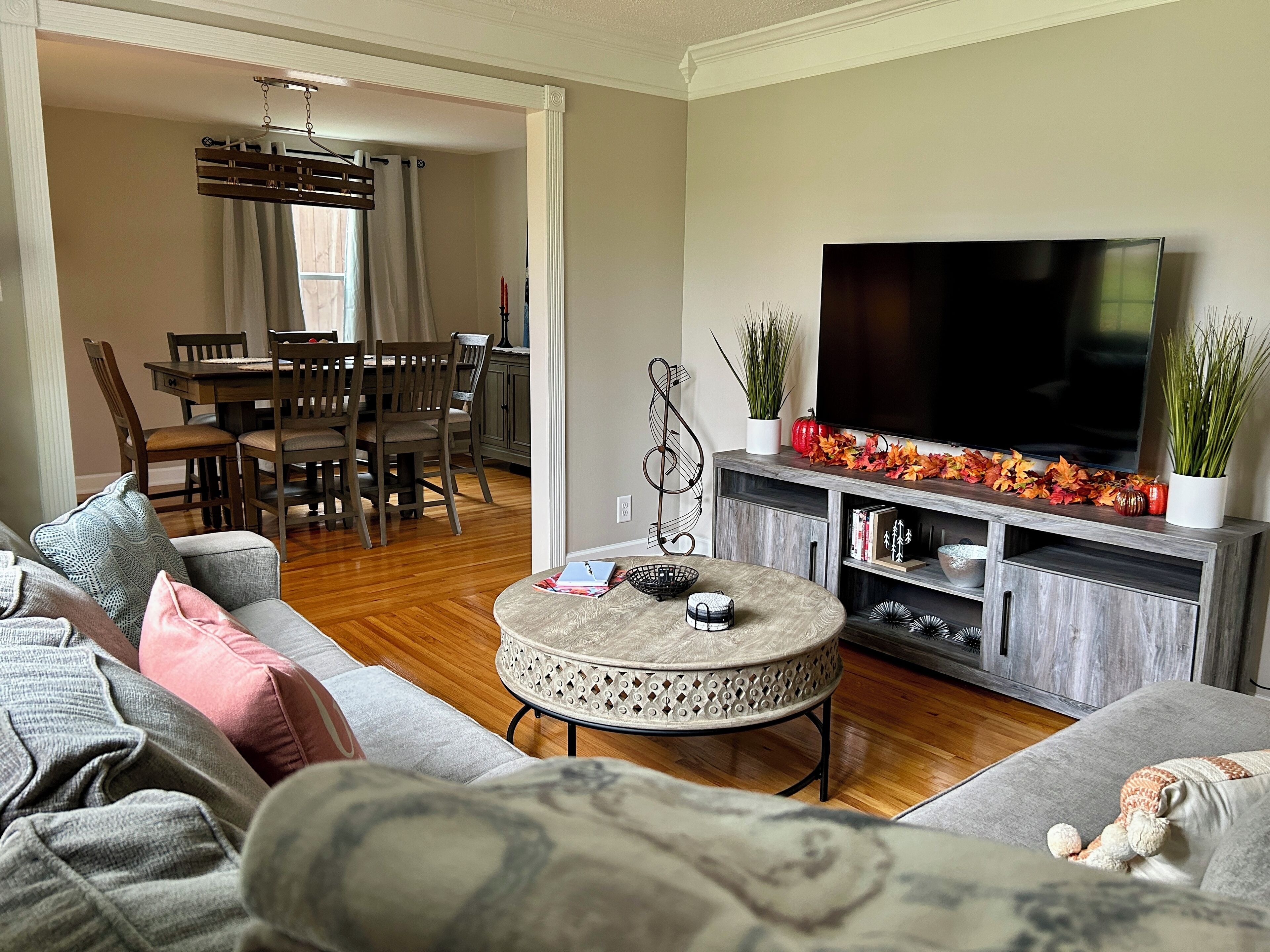 Uma sala de estar com sofá, mesa de centro, televisão e um espaço de jantar com cadeiras e mesa.