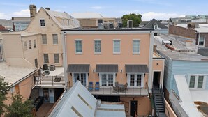 Um edifício de vários andares com telhado plano, várias janelas e uma pequena varanda com área de estar ao ar livre.