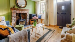 Un salon chaleureux avec une cheminée en briques, un téléviseur et une porte portant l’inscription « 101 ».