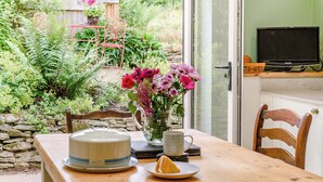 Une table en bois avec un gâteau, une assiette contenant une tranche d’orange et un vase rempli de fleurs.