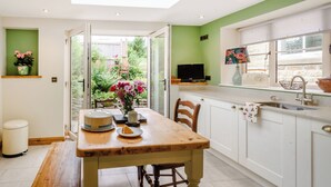 Une cuisine avec une table en bois, un évier et une fenêtre donnant sur un jardin.