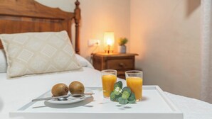Ein ordentlich gedecktes Frühstücksbrett mit zwei Kiwis, zwei Gläser Orangensaft und einer kleinen Zimmerpflanze auf einem weißen Tablett in einem Hotelzimmer.